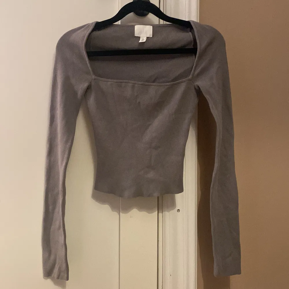 Säljer en stilren grå långärmad topp från H&M. Toppen har en fyrkantig halsringning och är tillverkad i ett mjukt material som ger en bekväm passform. Perfekt för både vardag och speciella tillfällen.. Yläosat.