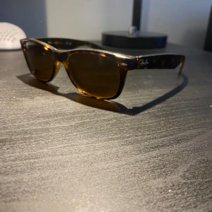 Solglasögon från Ray-Ban - Snygga solglasögon från Ray-Ban med en klassisk rektangulär form. Bågarna har ett stilrent leopardmönster i brunt och svart. Perfekta för en solig dag!