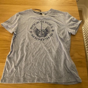 Grå t-shirt med rockmotiv - Säljer en grå t-shirt . Perfekt för dig som gillar rockstilen. T-shirten har korta ärmar och en rund halsringning. I stl xs men skulle säga att den också passar s! Inga defekter och skriv gärna innan du köper. Läs min bio innan du köper också!💗💗