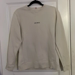 Beige sweatshirt från Les Deux - Säljer en stilren beige sweatshirt från Les Deux. Tröjan har en rund halsringning och långa ärmar. Perfekt för en avslappnad look. Storlek S