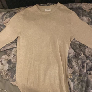 Beige tröja från Lindbergh - Säljer en stilren beige tröja från Lindbergh. Tröjan har långa ärmar och en diskret broderad detalj framtill. Perfekt för en avslappnad och snygg look. Storlek M