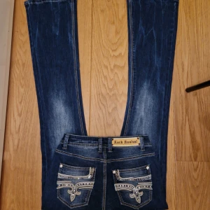 Washed Rock revival boot cut jeans  - Säljer ett par jättesnygga oanvända rock revivals med snygg design på backfickorna. Säljer eftersom dom är lite för långa för mig (är ca 162 cm). Priset kan disskuteras, det är bara och fråga för fler mått osv! ❤️