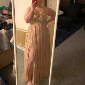 Lång klänning champagne rosé  - Lång klänning med öppen rygg & slits Champagne rosé  Stl. L passar M-XL (justerbara band i ryggen) Bra/ny skick, använd en gång Ny pris: 500kr