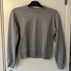 Grå sweatshirt från NA-KD - Säljer en stilren grå sweatshirt från NA-KD i storlek XS. Tröjan har en klassisk rund halsringning och långa ärmar med ribbade muddar. 
