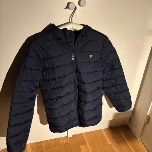 Mörkblå pufferjacka från Lyle & Scott - Säljer en mörkblå pufferjacka från Lyle & Scott Junior. Jackan har en dragkedja framtill och en liten logga på bröstet. Perfekt för kyligare dagar med sin vadderade design och huva. Skick 10/10 knappast andvänd super bra nu till vintern. Passar även mig som har storlek S. Ändas för 400 kr pris går att diskutera.