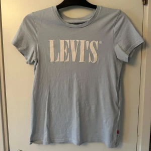 Ljusblå t-shirt från Levi's - Snygg ljusblå t-shirt från Levi's med stort vitt tryck på framsidan. Tillverkad i mjukt material för extra komfort.