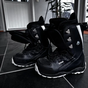 Svarta snowboard boots från Warp - Säljer ett par svarta snowboard boots från Warp med vita detaljer och snörning. Perfekta för vintersport och håller fötterna varma och bekväma i backen.❄️ Lite smuts på tårna, se sista bilden.  Kika och se om du ser något mer i min profil som du gillar så skickar jag med det till dig också!