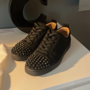Köp mina luobs för 1550 - Snygga svarta sneakers från Christian Louboutin med coola nitar på tån. Skorna har snörning och en stilren design som sticker ut. Perfekta för dig som vill ha något unikt i garderoben.