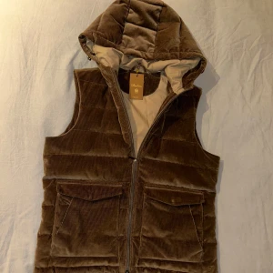 Brun manchester dunväst med huva - Snygg brun manchester dunväst från Stenströms med dragkedja och praktisk huva. Västen har två fickor framtill och är perfekt för kyligare dagar. Den quiltade designen ger en stilren look. Pris är diskuterbart, skriva vid frågor!😁