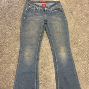 Blå bootcut jeans från Red Rivet - Snygga blå bootcut jeans från Red Rivet med dekorativa detaljer på bakfickorna. Tillverkade i en blandning av bomull, polyester och spandex för en bekväm passform. Perfekta för en avslappnad stil.