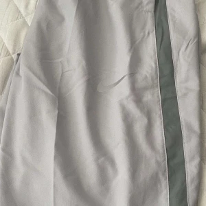 Grå träningsbyxor från Nike - Snygga grå träningsbyxor från Nike med en diskret logga på benet. Byxorna har en normal passform och är perfekta för träning eller en avslappnad dag. De har en elastisk midja för extra komfort.