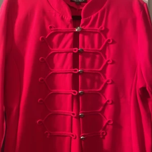 Röd jacka med dekorativa knappar - Snygg röd jacka med unika dekorativa knappar framtill. Jackan har en stilren design med långa ärmar och en elegant passform. Perfekt för att ge en färgklick till din outfit.