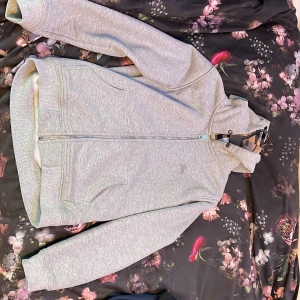 Grå burberry hoodie utan snöre  - Snygg grå burberry hoodie med dragkedja och ett stilrent broderat märke på bröstet. Insidan har det  klassiska mönster för burberry.  Perfekt för en avslappnad stil. Priset är inte hugget i sten           XS-S 