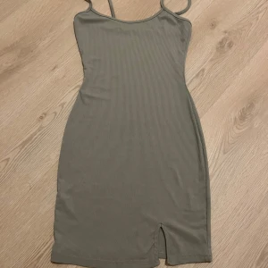 Grön ribbad klänning - Snygg grön ribbad klänning med smala axelband och en liten slits framtill. Perfekt för en stilren look.