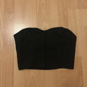 Svart randig korsett - Snygg svart korsett med vita ränder. Den har en klassisk design med hakknäppning. Perfekt för att ge en stilren och elegant look.