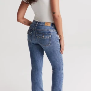 Blå jeans med hög midja - Snygga blå jeans med hög midja och klassisk femficksdesign. Jeansen har en straight passform och är perfekta för en avslappnad stil. De är tillverkade i ett slitstarkt denimtyg och har en knapp- och dragkedjestängning framtill.