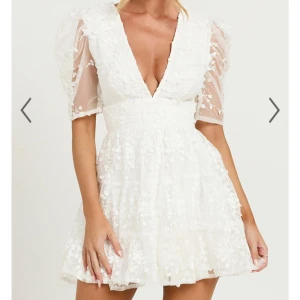 Vit blommig klänning med puffärmar från showpo  - Fin vit klänning med blommigt mönster och puffiga, transparenta ärmar. Den har en v-ringad design och en dragkedja i ryggen. Perfekt inför studenten. Klänningen är helt oanvänd med lappen kvar!!🩷