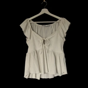 Vit blus med volangdetaljer - Säljer en söt vit blus från lager 157 med volangdetaljer och knytning framtill