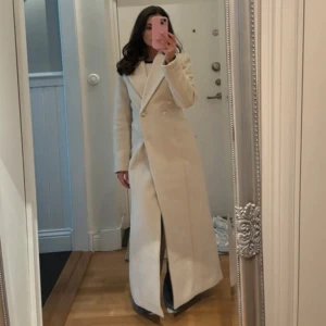 Beige lång kappa NA-KD  - Snygg beige kappa med lång design och knappar framtill🫶🏻från NAKDs samarbete med molly rustas✨ använd två gånger endast🫶🏻 storleken är xxs, men stor i storleken så skulle säga att det är som minst en xs, Orginalpris 1500kr