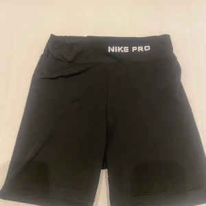 Svarta träningsshorts från Nike Pro - Säljer ett par svarta träningsshorts från Nike Pro. De är i nyskick och har en tight passform som är perfekt för träning. Shortsen är tillverkade i ett bekvämt och stretchigt material som andas bra.
