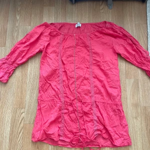 Röd blus från Love Attitude - Säljer en snygg rosa blus från Love Attitude. Blusen har trekvartsärmar och fina spetsdetaljer längs framsidan. 