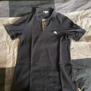 Svart pikétröja från Burberry - Säljer en snygg mörkblå nästan svart pikétröja från Burberry. Tröjan är i bra skick och har inget sletage. hör av er för frågor👍