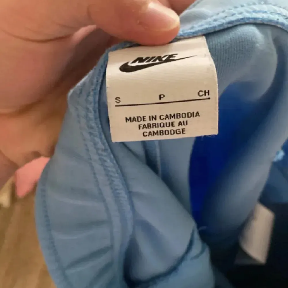 Säljer ett par blå mjukisbyxor från Nike i storlek S. Byxorna har en snygg tvåfärgad design med mörkare blå partier på framsidan och en dragkedja på baksidan. De har en elastisk midja med snörning för justerbar passform och är gjorda av mjukt och bekvämt material. Perfekta för träning eller en avslappnad dag hemma!. Jeans & Byxor.