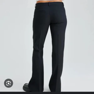 Svarta kostymbyxor - Säljer ett par svarta kostymbyxor från bikbok som är helt slutsålda. De är både stiliga och bekväma. byxorna är lågmidjade och har slits. Perfekta för alla tillfällen. Byxorna är i nyskick och har en dragkedja och knappar framtill. Har använt dem en gång då jag har växt ur de. nypris 499kr