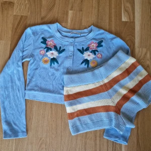 Blått stickat set från Zara - Säljer ett superfint stickat set från Zara i storlek S. Koftan har ett vackert blommigt broderi på framsidan och är croppad med långa ärmar. Shortsen är randiga och har en hög midja. De är i bra skick och mysiga att ha på sig 💐