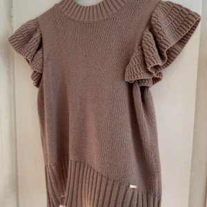 Beige stickad topp med volangärmar - Säljer en superfin beige stickad topp med volangärmar. Den är perfekt för både höst och vår, och kan stylas på många olika sätt. Toppen är i nyskick och har en normal passform. Den är både bekväm och trendig, perfekt för att lyfta vilken outfit som helst!