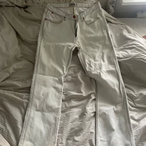 Vita jeans från Acne - Säljer ett par vita jeans från Acne i storlek 32/32. De är tillverkade av 100% bomull och har en klassisk femficksdesign med knapp och dragkedja framtill. Jeansen har en straight passform och är perfekta för både vardag och fest. De är i bra skick och redo för en ny ägare! näst intill oanvända. 