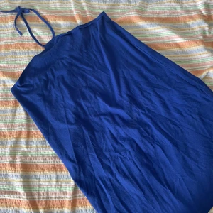 Blå klänning från b-watch - Säljer en blå klänning från b-watch. Den är ärmlös och har en enkel design med knytband vid halsen. Perfekt för sommarens fester eller en dag på stranden. Klänningen är i bra skick och redo för en ny ägare!
