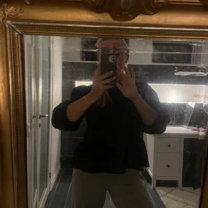 Blus - En svart blus med en volang längst ned och trekvartsarmar. Har en fin rygg med knytning. Storlek S.