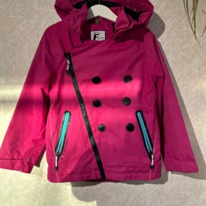 Vindjacka Five Seasons 110/116 - Söt vindjacka från Five Seasons  Strl 110/116   Gått sönder lite vid luvans knappar, se bild  Några små obehandlade fläckar finns  Två av knapparna fram är utbytta  Bra skick i övrigt!   Hund finns i hemmet