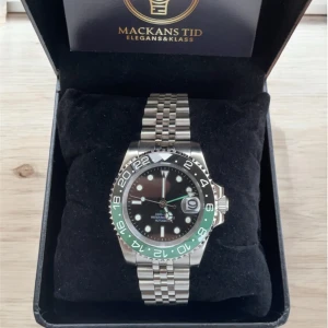 Seiko mod GMT - En fin sjävbyggd klocka i modellen GMT. Fina gröna detaljer med ett stainless steel band och saphire glas. Klockan är vatten tät och klarar av luft tryck ner till 100m under vattnet. Urverket är en automatisk NH35.