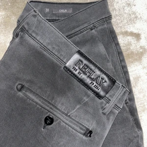 Grå byxor från Replay - Säljer ett par snygga grå byxor från Replay i storlek 31. De har en stilren design med knappar och dragkedja. Perfekta för både vardag och fest. Byxorna är i bra skick och redo för en ny ägare!