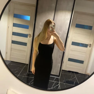 Lång svart klänning - Lång svart klänning med slits baktill, går precis ner marken. Hel men tyvärr lite nopprig på ena höften men går nog lätt att ta bort.