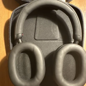 Sony hörlurar i svart fodral xm10005 - Säljer ett par Sony hörlurar i ett snyggt svart fodral. Perfekt för musikälskare som vill ha bra ljud och stilren design. Hörlurarna är bekväma och kommer med en laddningskabel. Perfekt för resor eller daglig användning. Hör av dig vid intresse!