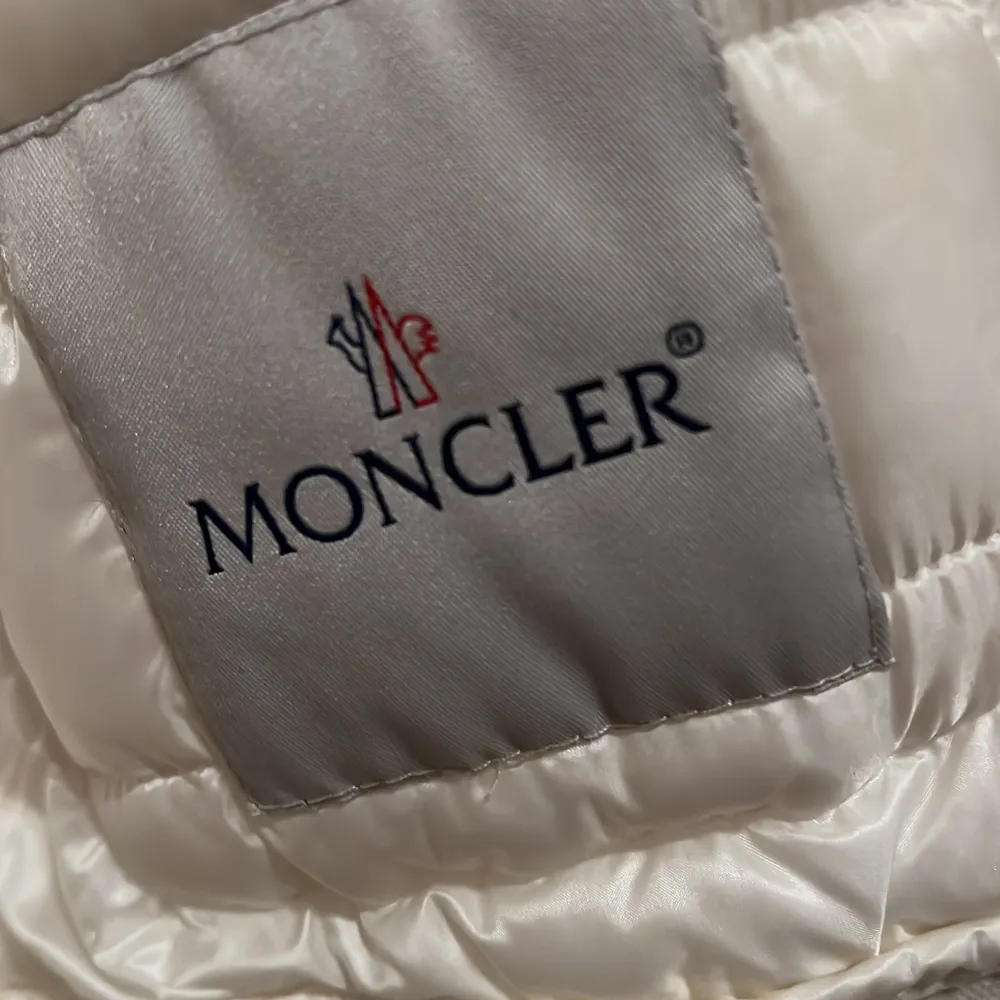 Säljer en snygg benvit dunjacka från Moncler i nyskick. Jackan har en quiltad design med dragkedja och två praktiska fickor framtill. Perfekt för kyliga höst- och vinterdagar. Den är både stilren och varm, vilket gör den till ett måste i garderoben!. Jackor.