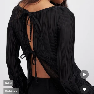 Svart långärmad topp med öppen rygg - Snygg svart topp med långa ärmar och en stilren, ribbad design. Toppen har en öppen rygg med knytband 🥰