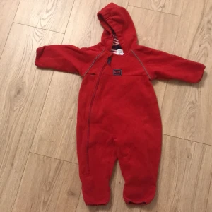 Höst overall - Röd overall med dragkedja på vänster sida. Den har tyvärr ett hål (se bild 3), därav det låga priset.
