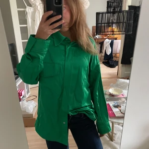 Grön skjorta med knappar - Säljer en snygg grön skjorta med knappar framtill. Den har en normal passform och långa ärmar, perfekt för både vardag och fest. Skjortan är i bra skick och kan stylas på många olika sätt. Passar perfekt till jeans eller kjol för en avslappnad look.