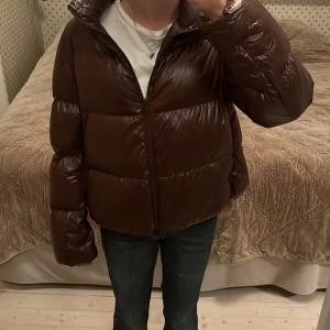 Glansig jacka - Jag säljer denna supersnygga vinterjacka då jag köpt en annan! Den är använd en vinter men har inga defekter. Supersnygg och glansig brun färg på jackan, jackan är i storlek S och är från uniqlo