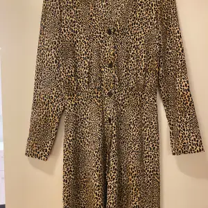 Snygg leopardmönstrad klänning från Divided i storlek S. Klänningen har långa ärmar och knappar framtill, perfekt för en trendig look. idealisk för både vardag och fest. 🐆✨