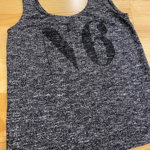 Gråmelerad linnetopp från NLY Trend - Snygg gråmelerad linnetopp från NLY Trend i storlek S. Perfekt för en avslappnad stil, med ett stort tryck på framsidan. Denna topp är både bekväm och trendig. Passar utmärkt till vardags eller en chill dag ute.