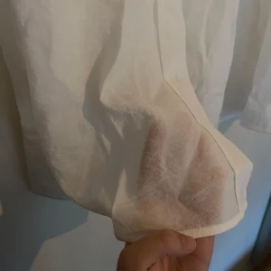 Vit genomskinlig skjorta, strl 38 - Vit långärmad genomskinlig skjorta med stor krage och rundade sidor. Testad men aldrig använd. 