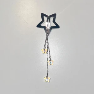 Gulligt stjärn hårspänne - Handgjort och oanvänt. Silvrigt stjärnformatt hårspänne med 3 mindre som hänger ner som är genomskinliga och skiftar i blåa färger.