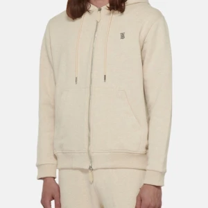 Beige burberry hoodie med dragkedja - Säljer en stilren beige burberry hoodie med dragkedja framtill. Den har en klassisk passform med långa ärmar och en praktisk huva med dragsko. Perfekt för en avslappnad look!