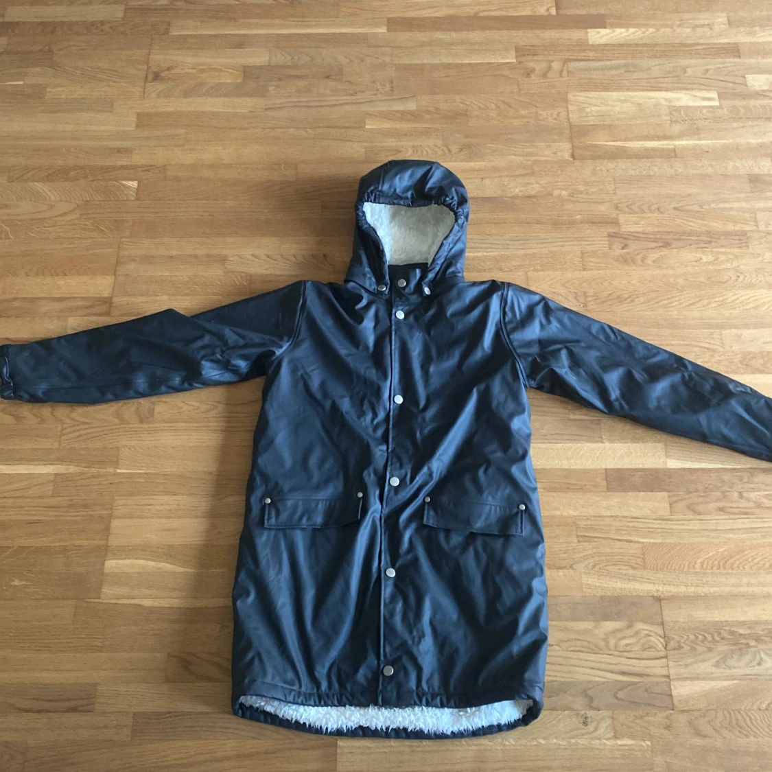 Svart regnkappa med fluffigt tyg inuti 