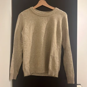 Beige stickad tröja - Säljer en mysig beige stickad tröja som är perfekt för kyliga dagar. Tröjan har långa ärmar och ribbstickade muddar vid ärmslut och nederkant. Den passar perfekt nu till hösten🤗